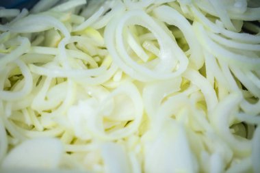 Donmuş soğan halkaları ve ince buz kaplamalı yarım halkalar yakın çekim. Süpermarketlerde raf ömrünün uzatılması ve bozulabilir hasat kalitesinin korunması için perakende paketlemeye hazırlar..