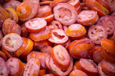 İnce buz kaplamalı, dondurulmuş kırmızı domateslerin yakın çekimi. Süpermarketlerde raf ömrünün uzatılması ve bozulabilir hasat kalitesinin korunması için perakende paketlemeye hazırlar..