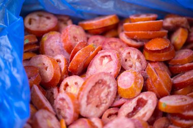 İnce buz kaplamalı, dondurulmuş kırmızı domateslerin yakın çekimi. Süpermarketlerde raf ömrünün uzatılması ve bozulabilir hasat kalitesinin korunması için perakende paketlemeye hazırlar..