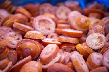 İnce buz kaplamalı, dondurulmuş kırmızı domateslerin yakın çekimi. Süpermarketlerde raf ömrünün uzatılması ve bozulabilir hasat kalitesinin korunması için perakende paketlemeye hazırlar..