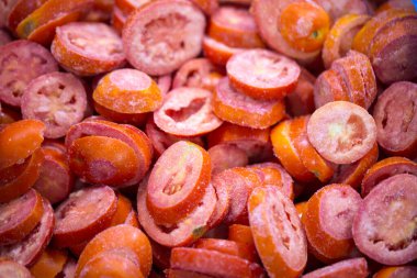 İnce buz kaplamalı, dondurulmuş kırmızı domateslerin yakın çekimi. Süpermarketlerde raf ömrünün uzatılması ve bozulabilir hasat kalitesinin korunması için perakende paketlemeye hazırlar..