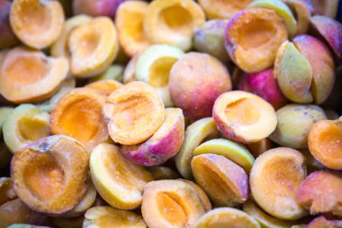 İnce buz kaplamalı, şok olmuş, olgun, pembe kayısı yarımları. Süpermarketlerde raf ömrünün uzatılması ve bozulabilir hasat kalitesinin korunması için perakende paketlemeye hazırlar..