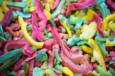 Kırmızı, sarı ve yeşil çeşitleri de içeren dondurulmuş tatlı biber karışımına yakın çekim. Süpermarketlerde perakende paketlemeye ve bozulabilir hasat kalitesini korumaya hazır..