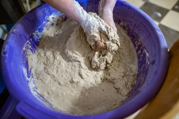 El yapımı ekmek hazırlama işlemi sırasında büyük plastik bir kabın içinde hamur yoğuran eller. Hamur yapış yapış ve yapış, aktif karışımı gösteriyor..