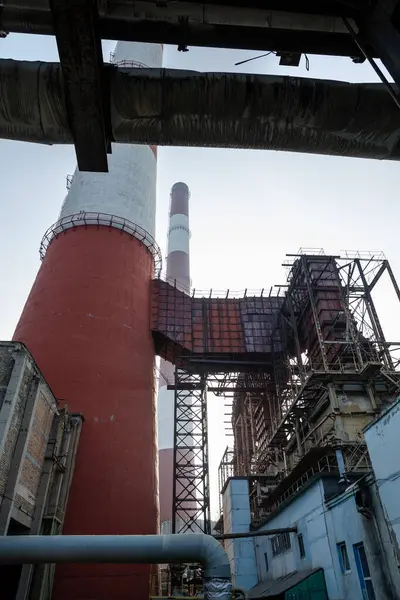 Yüksek kapasiteli bir termik santralde devasa bir gaz egzoz sistemi. Yüksek kırmızı-beyaz bacalar 150 metreyi aşarak emisyon yönetimi ve endüstriyel hava dolaşımını kolaylaştırıyor..