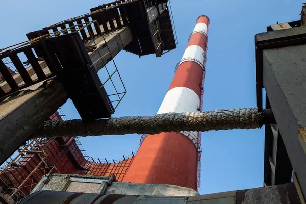 Yüksek kapasiteli bir termik santralde devasa bir gaz egzoz sistemi. Yüksek kırmızı-beyaz bacalar 150 metreyi aşarak emisyon yönetimi ve endüstriyel hava dolaşımını kolaylaştırıyor..