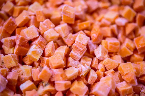 İnce buz kaplamalı dondurulmuş kırmızı dolma biber küplerinin yakın çekimi. Perakende satışlar ve bozulabilir hasatların korunması için uzun raf ömrü sağlamak üzere ambalaj işlemine hazırlandı.