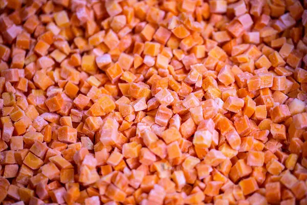 İnce buz kaplamalı dondurulmuş kırmızı dolma biber küplerinin yakın çekimi. Perakende satışlar ve bozulabilir hasatların korunması için uzun raf ömrü sağlamak üzere ambalaj işlemine hazırlandı.