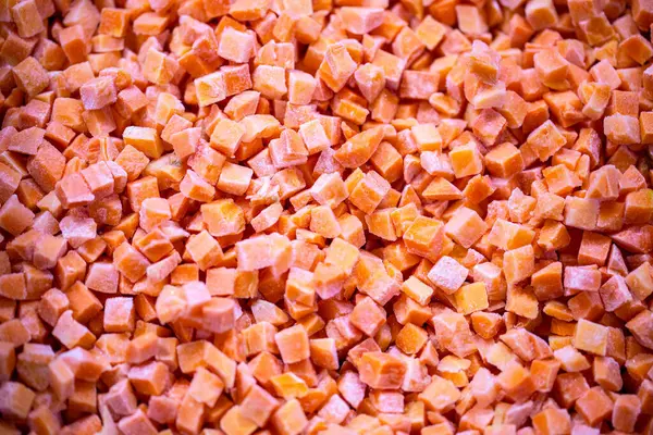 İnce buz kaplamalı dondurulmuş kırmızı dolma biber küplerinin yakın çekimi. Perakende satışlar ve bozulabilir hasatların korunması için uzun raf ömrü sağlamak üzere ambalaj işlemine hazırlandı.