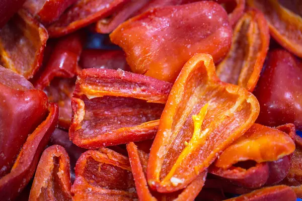 Dondurulmuş kırmızı biber parçalarının yakın planında ince bir buz tabakası ve korunmuş tazelik. Perakende satışlar ve bozulabilir hasatların korunması için uzun raf ömrü sağlamak üzere ambalaj işlemine hazırlandı.