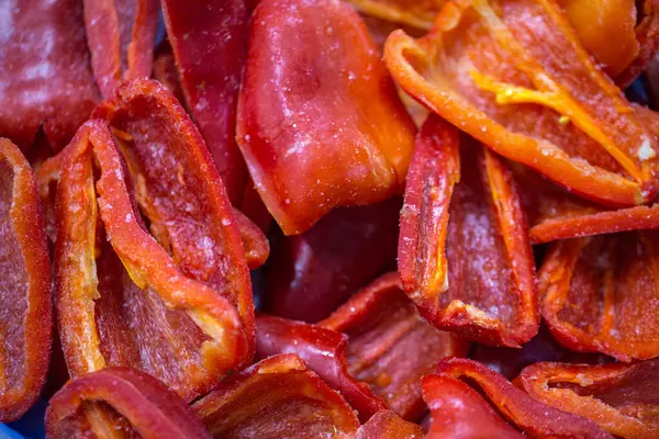 Dondurulmuş kırmızı biber parçalarının yakın planında ince bir buz tabakası ve korunmuş tazelik. Perakende satışlar ve bozulabilir hasatların korunması için uzun raf ömrü sağlamak üzere ambalaj işlemine hazırlandı.