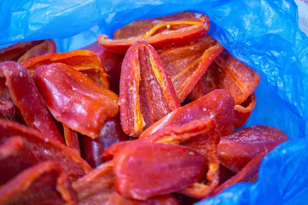 Dondurulmuş kırmızı biber parçalarının yakın planında ince bir buz tabakası ve korunmuş tazelik. Perakende satışlar ve bozulabilir hasatların korunması için uzun raf ömrü sağlamak üzere ambalaj işlemine hazırlandı.