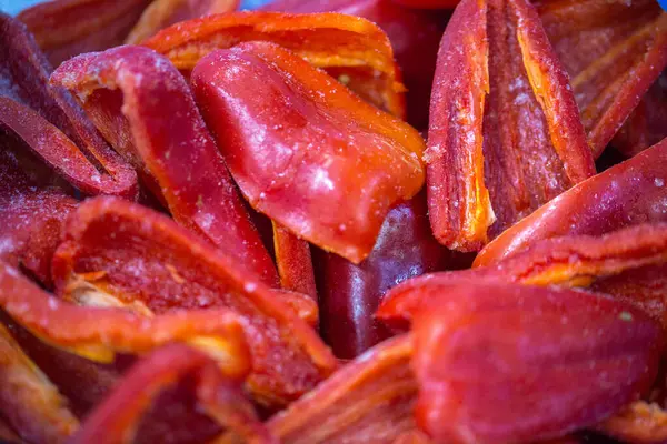 Dondurulmuş kırmızı biber parçalarının yakın planında ince bir buz tabakası ve korunmuş tazelik. Perakende satışlar ve bozulabilir hasatların korunması için uzun raf ömrü sağlamak üzere ambalaj işlemine hazırlandı.