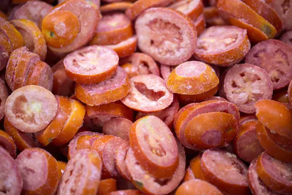 İnce buz kaplamalı, dondurulmuş kırmızı domateslerin yakın çekimi. Süpermarketlerde raf ömrünün uzatılması ve bozulabilir hasat kalitesinin korunması için perakende paketlemeye hazırlar..