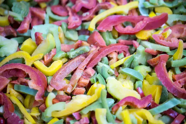 Kırmızı, sarı ve yeşil çeşitleri de içeren dondurulmuş tatlı biber karışımına yakın çekim. Süpermarketlerde perakende paketlemeye ve bozulabilir hasat kalitesini korumaya hazır..