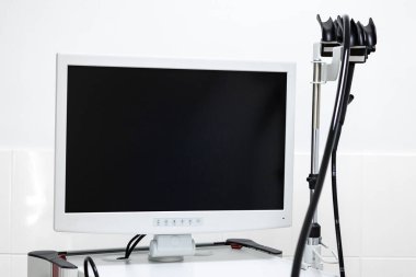 Geniş bir monitörü, işleme ünitesi ve endoskopisi olan modern bir endoskopi sistemi, duvarları fayanslarla kaplı, temiz bir tıbbi odadaki seyyar bir arabada bulunuyor..