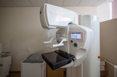 Çift etkileşimli ekranları olan modern bir mammografi makinesi, temiz bir tıbbi odada, tanı taraması için hazır bekliyor.
