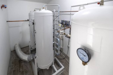 Geniş beyaz tankları, boruları ve göstergeleri olan modern bir oksijen üretim tesisi sağlık tesislerine tıbbi düzeyde oksijen sağlıyor. Steril bir malzeme odasında duruyor..