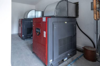 Dakikada 3220 litre kapasiteli iki büyük endüstriyel vida kompresörü yalıtımlı kanallı bir odada duruyor ve endüstriyel makineleri gösteriyor..