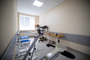 Rehabilitasyon odasında bir yürüyüş makinesi, koşu bandı, sabit bisiklet, hasta iyileştirme için tasarlanmış manipülatif araçlar da dahil olmak üzere çeşitli egzersiz ve fizik tedavi ekipmanları yer alıyor..