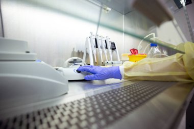 Pipetler ve bir karıştırıcı da dahil olmak üzere DNA / RNA çıkarma ekipmanı bir laboratuvardaki havalandırmalı güvenlik dolabında bulunuyor.