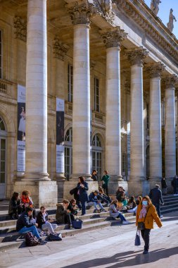 Bordeaux, Fransa - 23 Kasım 2021: İnsanlar klasik sütunlar ve dekoratif cephelerle Grand Theatre de Bordeaux 'nun basamaklarında rahatlar. Bordeaux, Gironde, Yeni Aquitaine, Fransa.