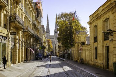Bordeaux, Fransa - 23 Kasım 2021: Rue Vital Carles 'da klasik binaların çerçevelediği Bordeaux Katedrali' nin kulelerine bakan tramvay rayları. Bordeaux, Gironde, Yeni Aquitaine, Fransa.