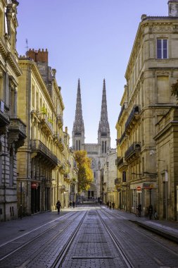 Bordeaux, Fransa - 23 Kasım 2021: Rue Vital Carles 'da klasik binaların çerçevelediği Bordeaux Katedrali' nin kulelerine bakan tramvay rayları. Bordeaux, Gironde, Yeni Aquitaine, Fransa.