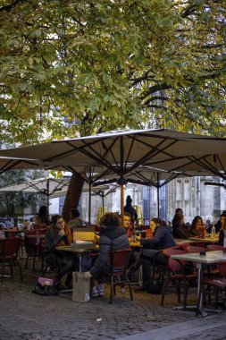 Bordeaux, Fransa - 23 Kasım 2021: Sonbahar yeşillikleri olan bir açık kafede, bir kadın izlerken, bir erkek bir karton kutudan yeni bir çift beyaz spor ayakkabı çıkarır. Bordeaux, Yeni Akitanya, Fransa.
