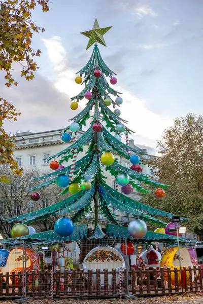 Renkli süslerle süslenmiş büyük modern Noel ağacı ve Quinconces yerindeki neşeli çocuk arabaları ve klasik binalarla çevrili bir yıldız. Bordeaux, Gironde, Yeni Aquitaine, Fransa