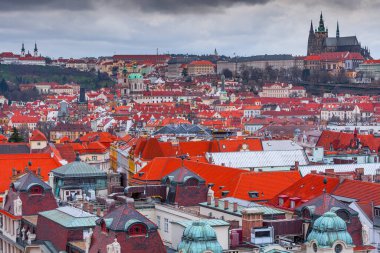 Prag Kalesi 'nin panoramik bir görüntüsü, Eski Belediye Binası Kulesi' nden elde edilen görüntülerde, dramatik bir gökyüzü altında Prag, Çek Cumhuriyeti 'ndeki görkemli gotik katedral ve kırmızı çatılı binalar sergileniyor..