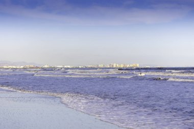 Valencia, İspanya 'da Malvarrosa' nın güneşli sonbahar plajlarında yaz titreşimleri. Deniz kıyısındaki engin, pürüzsüz kumlar tatilcileri köpüklü dalgalar boyunca yapayalnız yürüyüşlere çeker..