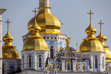 Ukrayna 'nın başkenti Kyiv' deki St. Michael 's Altın Kubbe Manastırı' nın parlak altın kubbeleri. Ukrayna Barok cephesinde mavi duvarlar, süslemeler ve altın haçlar yer alıyor..
