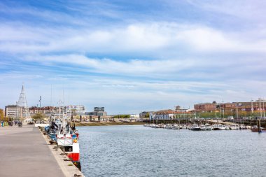 Güneşli bir günde Santander, Cantabria, İspanya 'daki limanın geniş bir manzarası. Balıkçı tekneleri ve eğlence gemileri rıhtım boyunca demirlemiş..