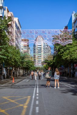 Alicante, İspanya 14 Kasım 2021: Melia tarafından Alicante 'de bulunan Alicante Gran Sol Oteli' nin cephesinde büyük bir duvar resmi bulunmaktadır. Noel ışıkları olan cadde restoran ve dükkanlarla dolu..