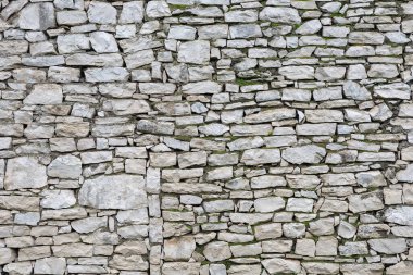 Well-preserved traditional stone wall showcasing a patchwork of various stones with spots of lush green moss