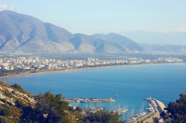 Yamaçtan panoramik bir manzara Finike 'nin geniş kıyılarını, marinası ve kentsel manzarasıyla bir dağ zeminine karşı yakalar..