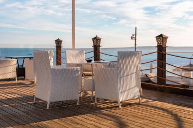 Okyanus manzarası manzaralı beyaz hasır sandalyeli deniz kenarı terası.