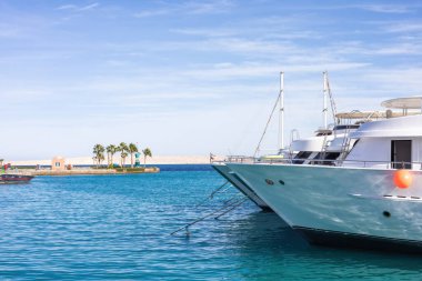 Lüks yatlar berrak mavi sularla dolu sakin bir marinada demirli.