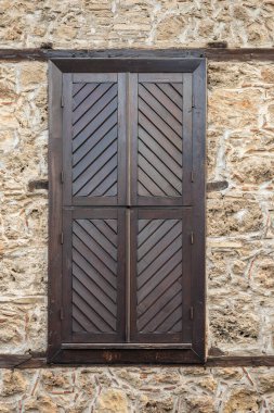 Rustic wooden shuttered window on old stone wall with diagonal patterns. clipart