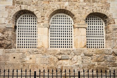 Kemerli camları ve demir çitleri olan tarihi taş bina..