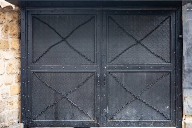 Rustic black metal gate with stone wall backdrop. clipart