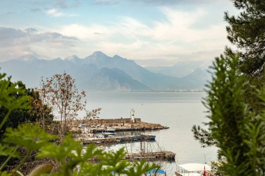 Sakin sularda uzak dağlar ve deniz feneri olan sakin bir liman..