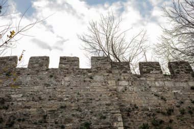 Bulutlu gökyüzünün altında siperleri olan Ortaçağ Taş Kale Duvarı.