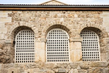 Üç kemerli pencere ve ızgaralı tarihi taş bina.