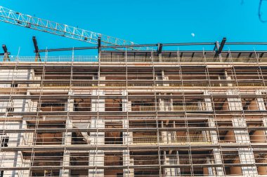 Açık mavi gökyüzüne karşı iskelesi olan inşaat alanı.