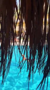 Saman örtüsü güneşli bir günde canlı yüzme havuzuna bakar..