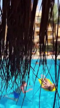 İnsanlar sazdan çatı gölgesinde havuzda dinleniyorlar..