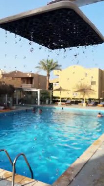 Güneşli bir günde açık havuz başındaki duşa su sıçratır..