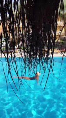 İnsanlar havuzda yüzüyor. Sazlı çatıya odaklan..